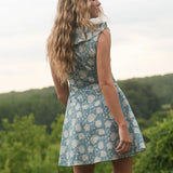 Woman in a floral dress standing outdoors with greenery in the background