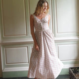 Woman wearing a floral dress standing in a room with paneled walls.