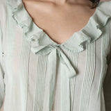 mint colored long sleeve top with ruffles and a bow