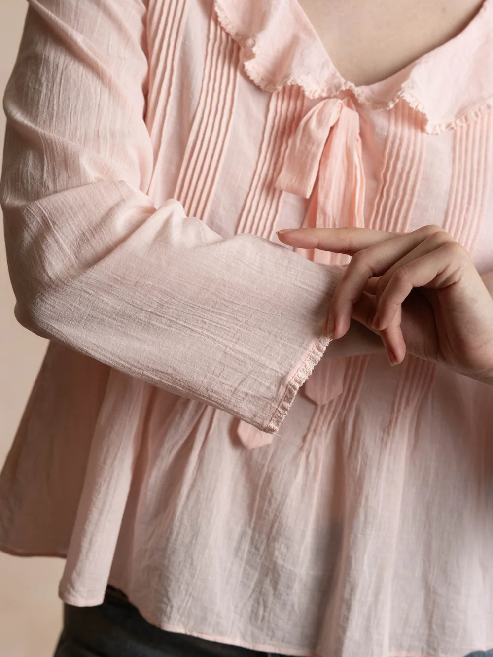 close up of a pink pintucked top with a bow