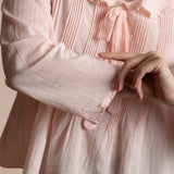 close up of a pink pintucked top with a bow