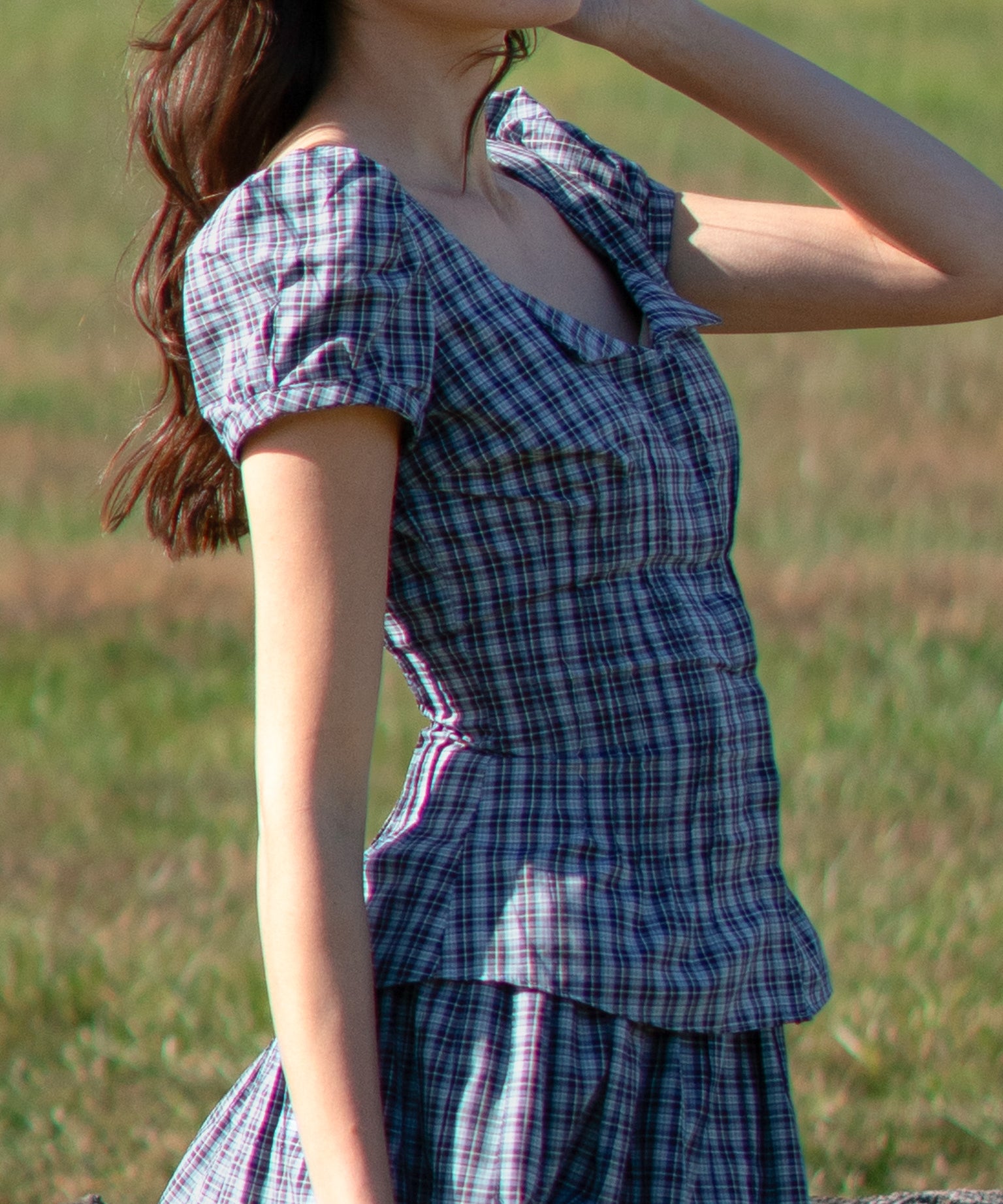 Woman wearing a blue plaid set standing in a grassy field