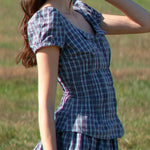 Woman wearing a blue plaid dress standing in a grassy field