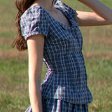 Woman wearing a blue plaid dress standing in a grassy field
