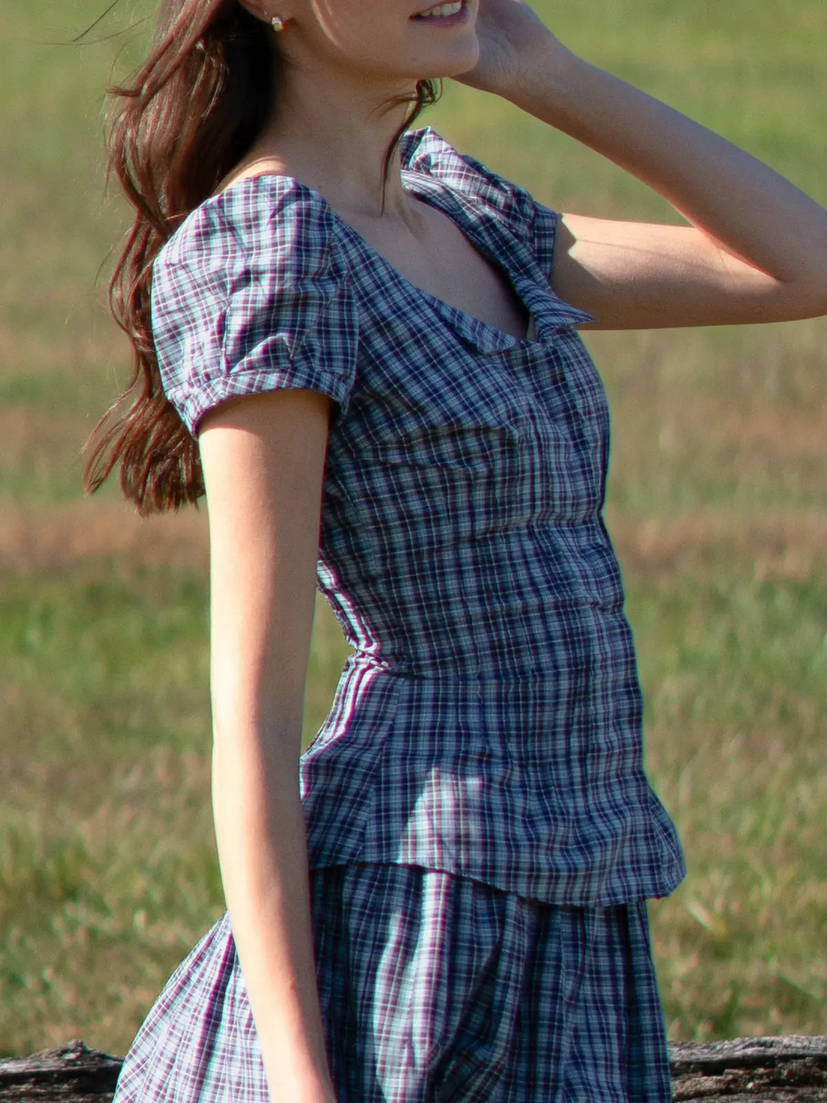 Woman wearing a blue plaid dress standing in a grassy field