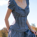 Woman wearing a blue plaid set with a blurred natural background