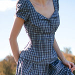 Woman wearing a blue plaid dress with a blurred natural background