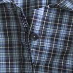 Close-up of a blue and black plaid shirt with a button.
