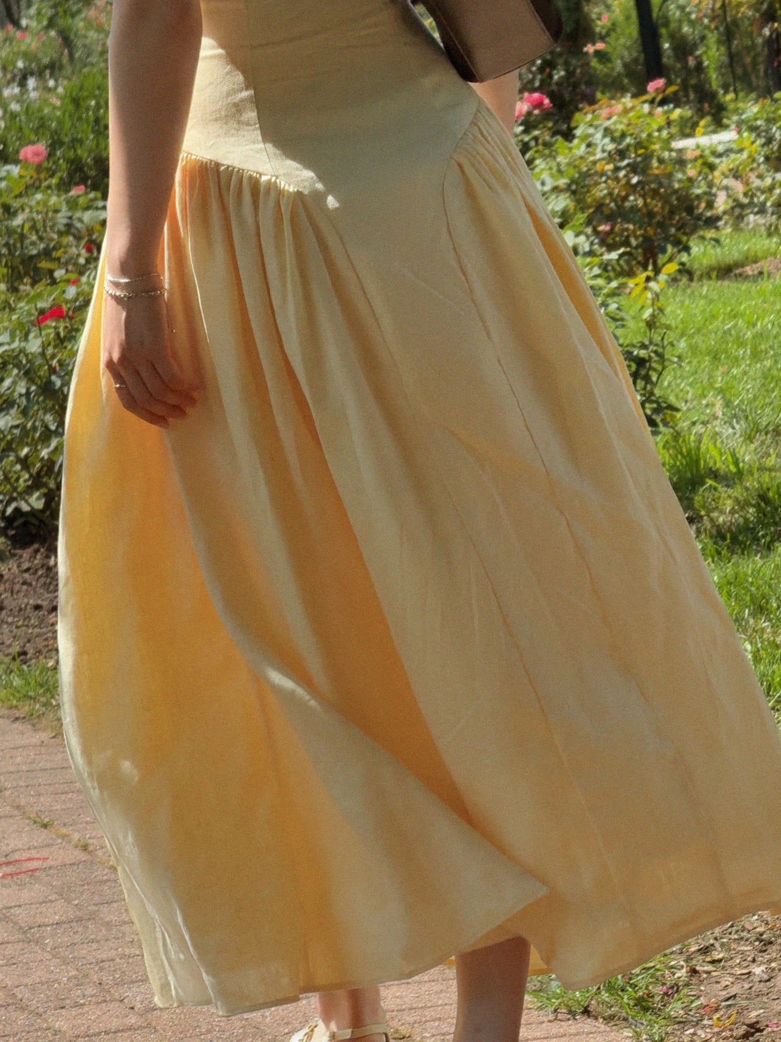 Person wearing a yellow skirt in an outdoor setting with greenery.