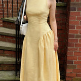 Woman wearing a yellow dress standing on a staircase with a brick wall background
