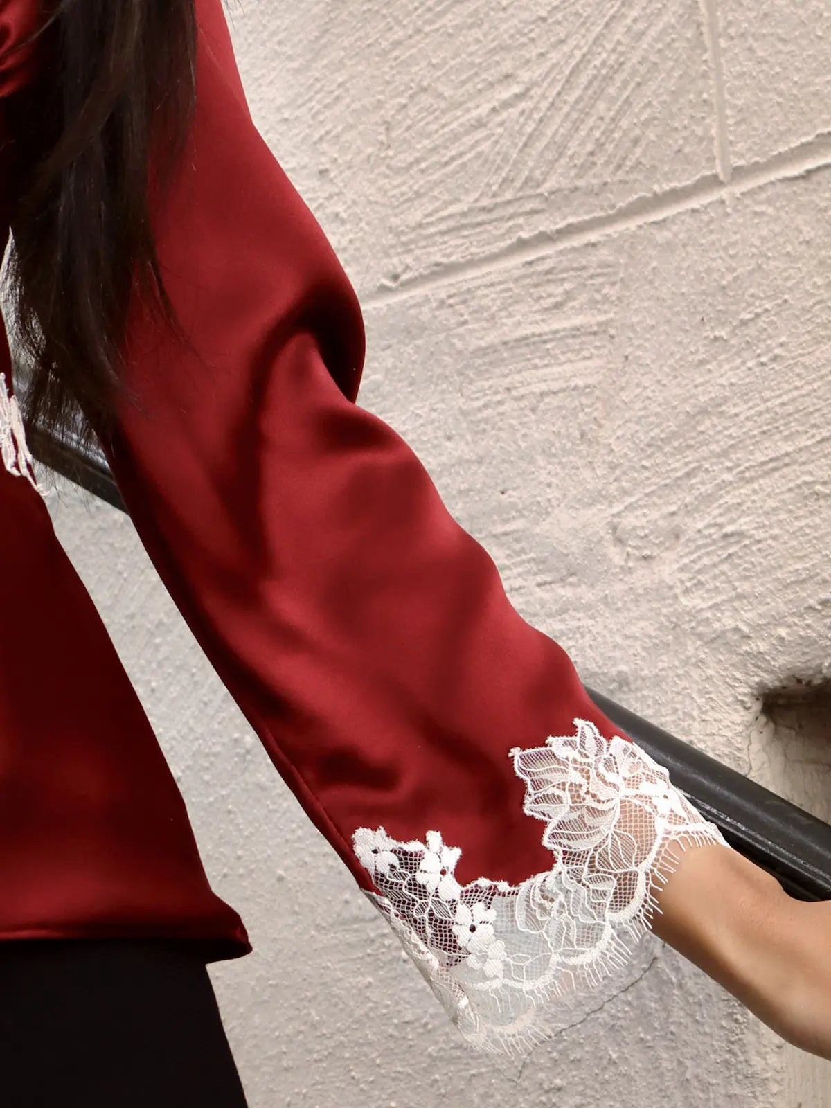 Close-up of a red garment with lace detailing on a textured surface