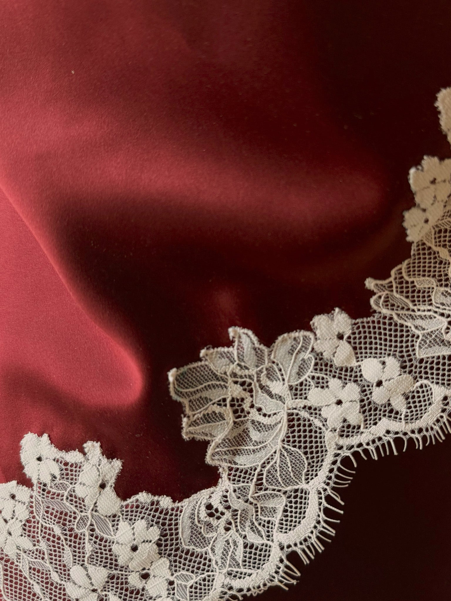 Close-up of white lace trim on a red fabric background