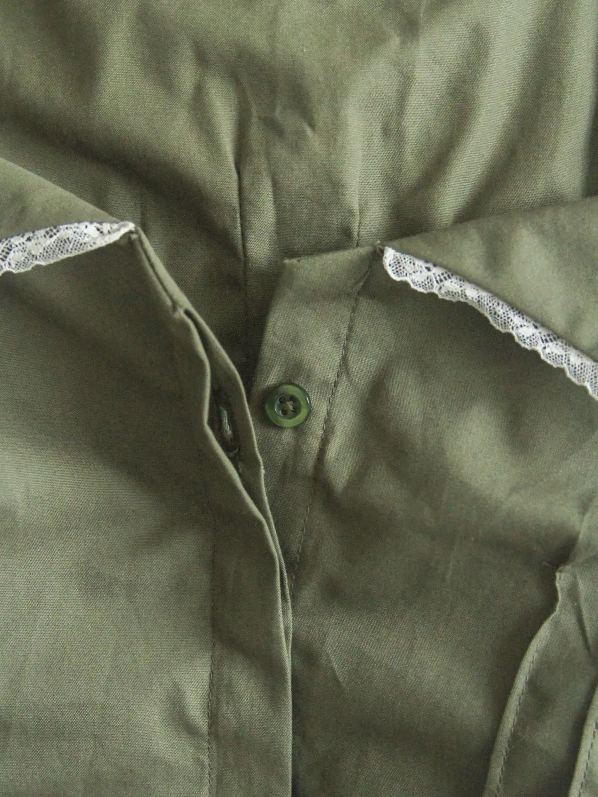 Close-up of a green shirt with lace trim on the collar.