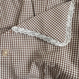 Brown and white checkered fabric with lace trim on a wooden surface