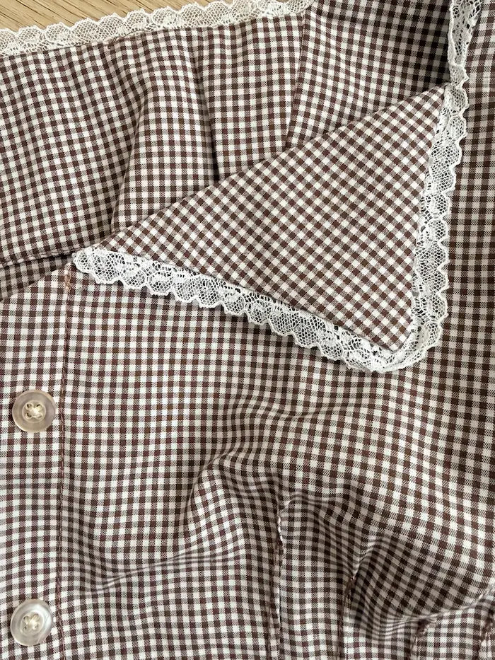 Brown and white checkered fabric with lace trim on a wooden surface