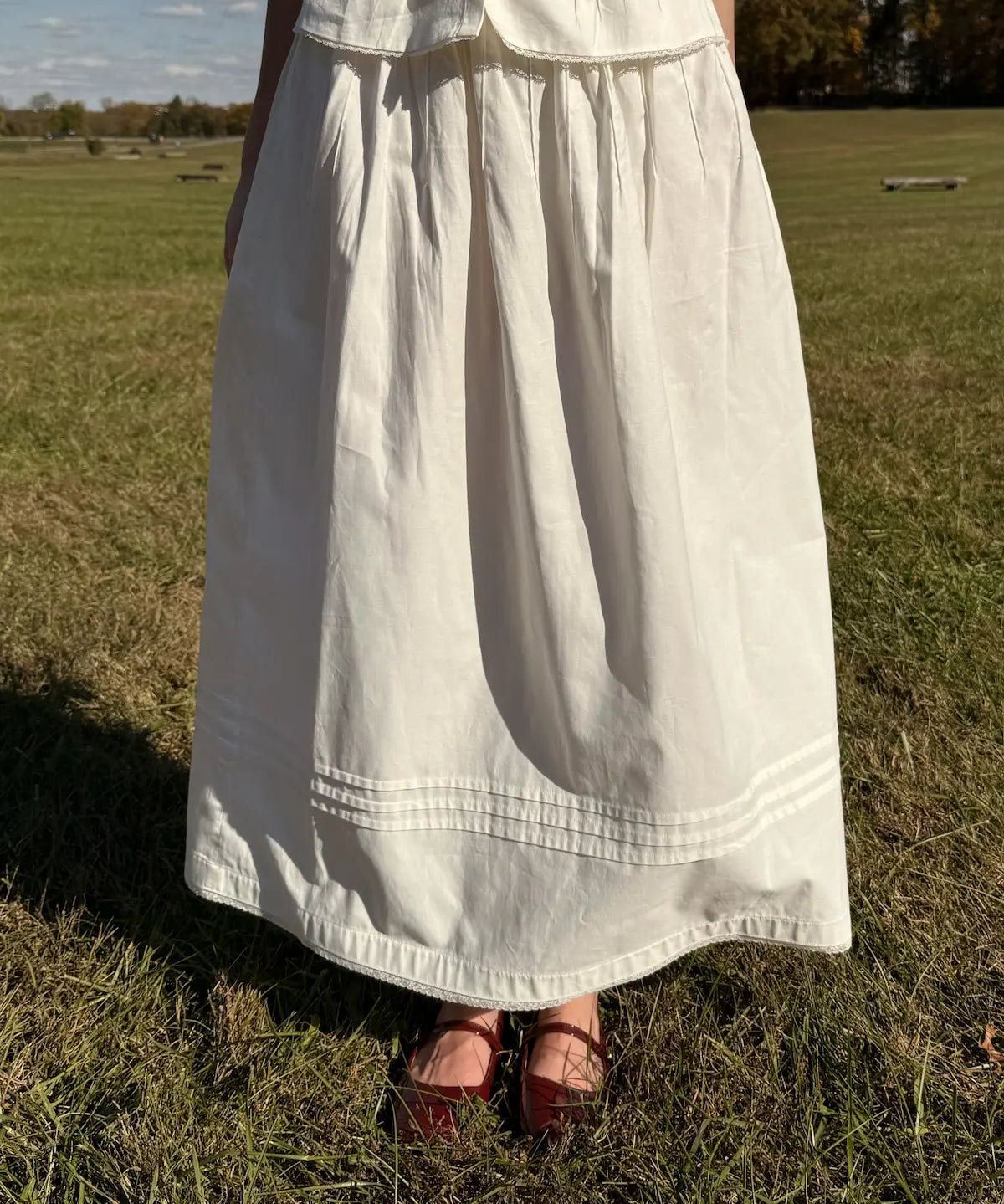 Person wearing a white dress standing in a grassy field