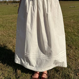 Person wearing a white dress standing in a grassy field