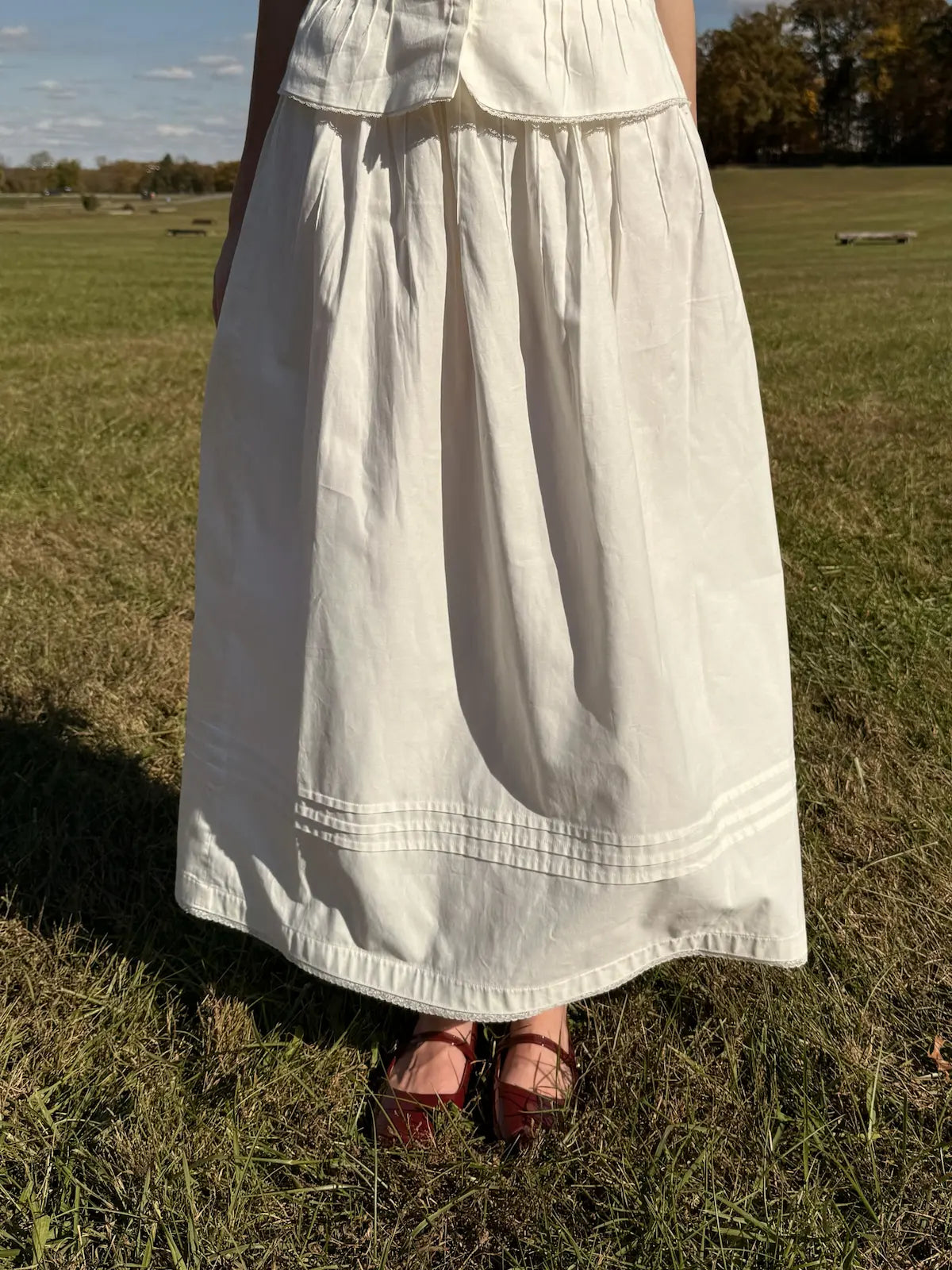 Person wearing a white dress standing in a grassy field