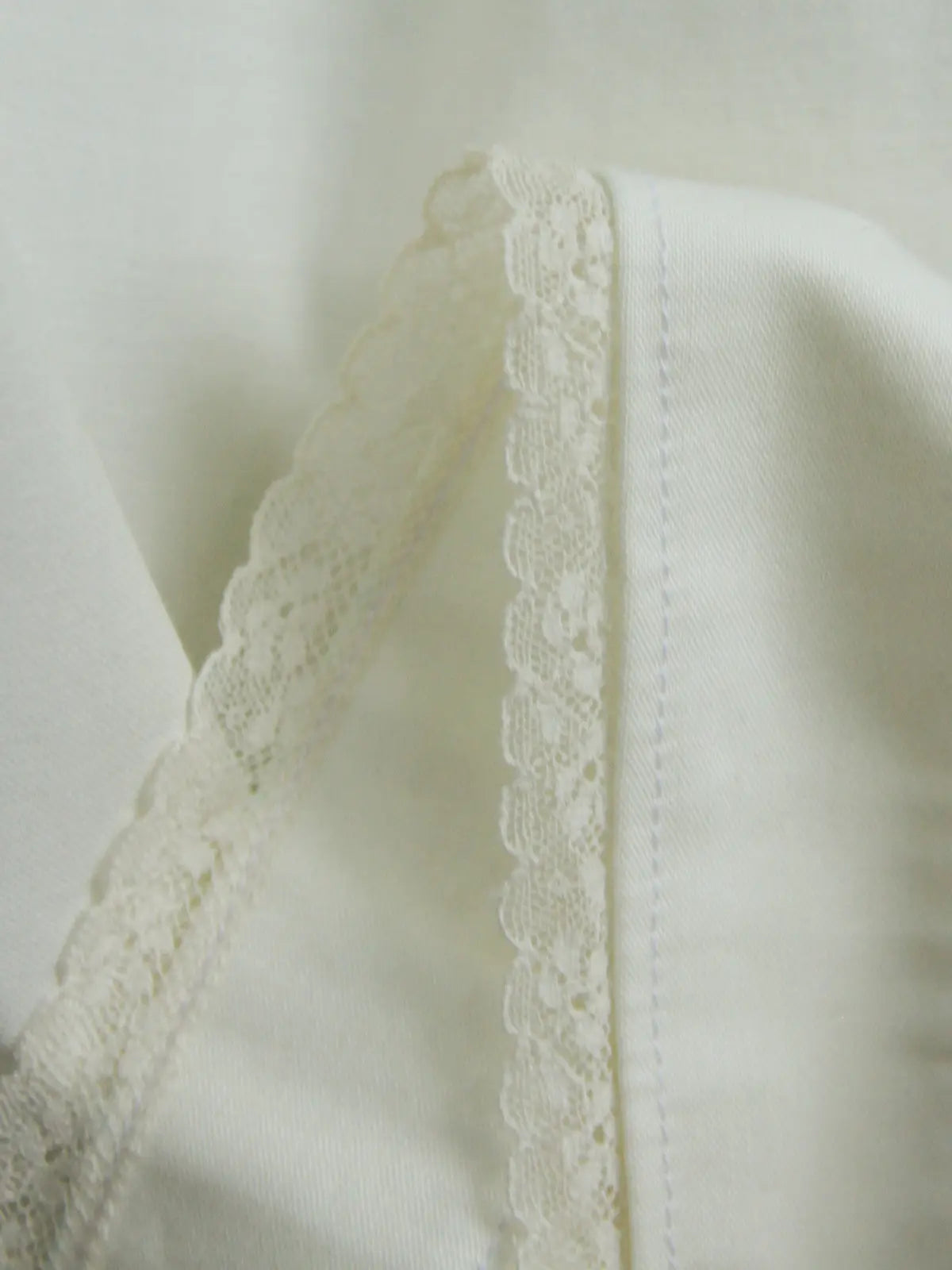 Close-up of a white fabric with lace trim on a light background