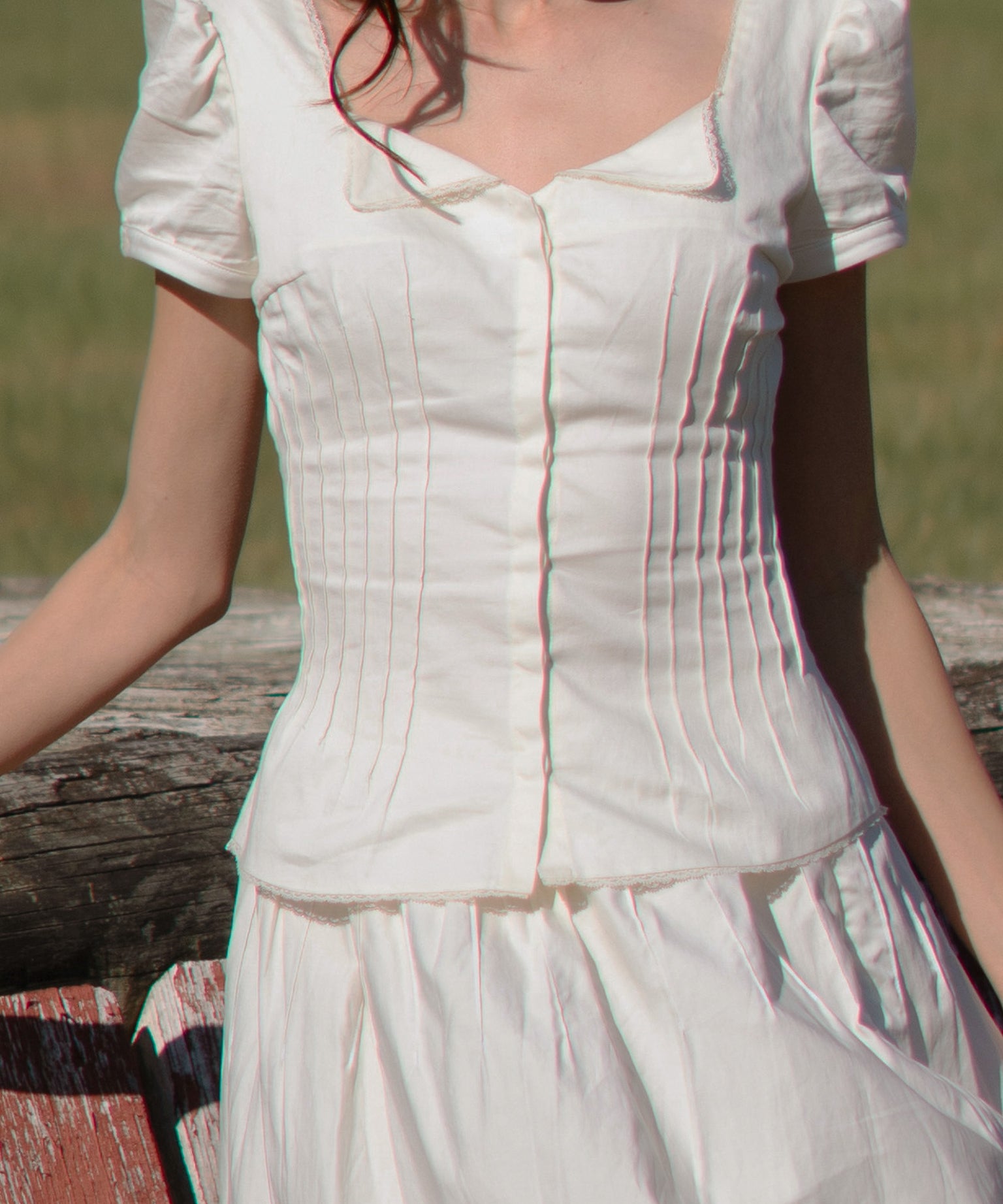 White dress with puffed sleeves worn by a person, standing against a natural background.