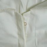 Close-up of a white shirt with lace trim on a light background