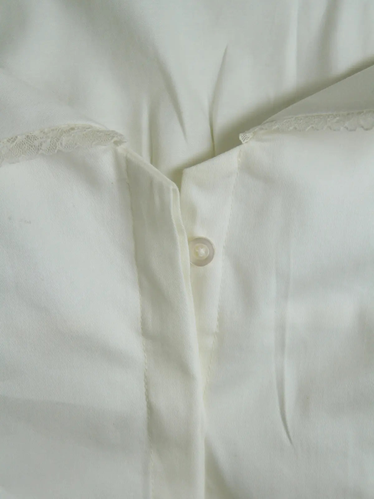 Close-up of a white shirt with lace trim on a light background