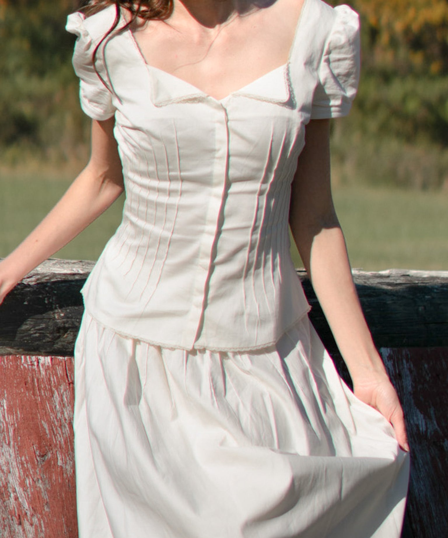 Woman wearing a white dress with puffed sleeves against a natural background